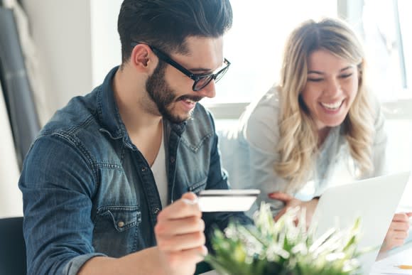 Man and woman looking at a tablet, man holding a payment card.