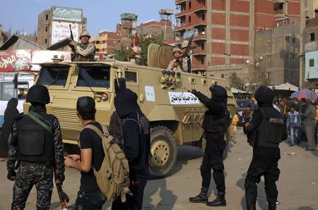 Police stand guard as an army vehicle approaches as they prepare for more possible protests in the eastern suburb of Mataryia, Cairo, November 28, 2014. REUTERS/Asmaa Waguih