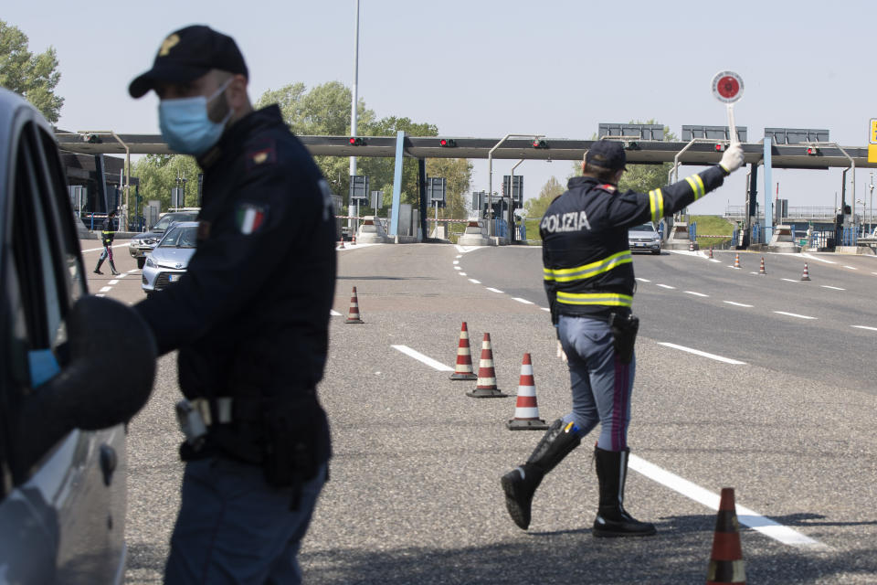 Police officers stop cars at the Melegnano highway barrier entrance, near Milan, Italy, Saturday, April 11, 2020. Using helicopters, drones and stepped-up police checks to make sure Italians don't slip out of their homes for the Easter holiday weekend, Italian authorities are doubling down on their crackdown against violators of the nationwide lockdown decree. The new coronavirus causes mild or moderate symptoms for most people, but for some, especially older adults and people with existing health problems, it can cause more severe illness or death. (AP Photo/Luca Bruno)