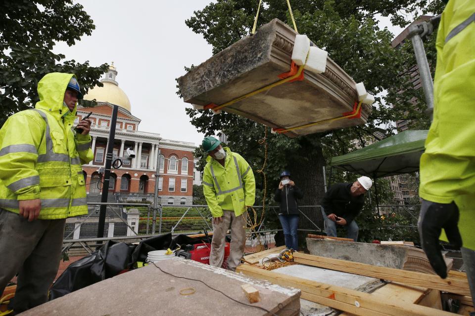 Workers inspect the top cornice stone as it is lifted from the Shaw 54th Regiment memorial opposite the Statehouse, Friday, July 17, 2020, in Boston. Amid the national reckoning on racism, the memorial to the first Black regiment of the Union Army, the Civil War unit popularized in the movie "Glory,” is facing scrutiny. (AP Photo/Michael Dwyer)