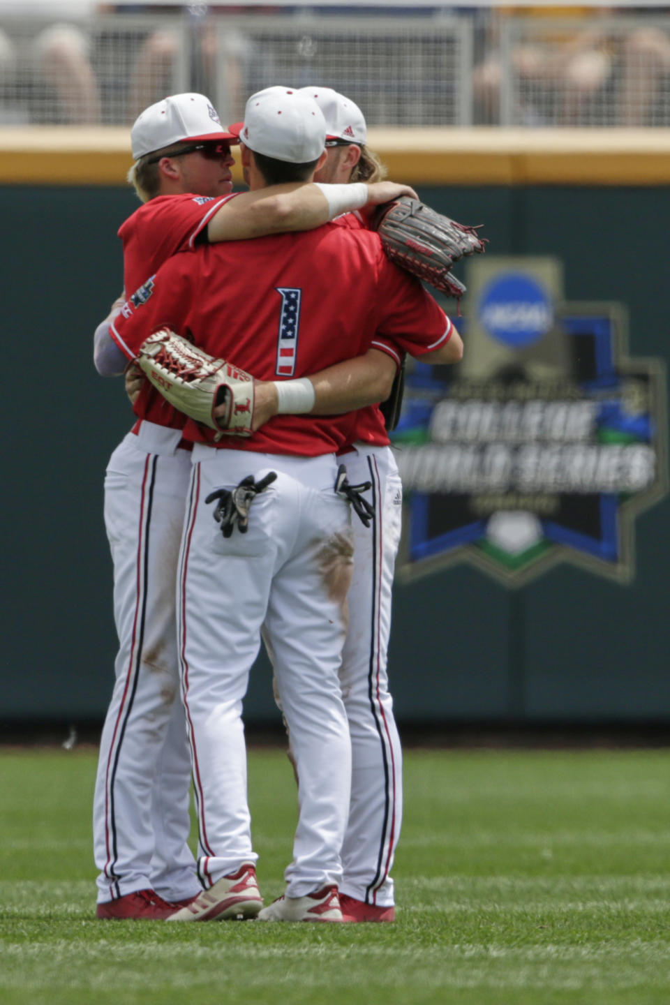 Louisville outfielders including Drew Campbell (1) hug in the outfield following an NCAA College World Series baseball elimination game against Auburn in Omaha, Neb., Wednesday, June 19, 2019. Louisville won 5-3. (AP Photo/Nati Harnik)