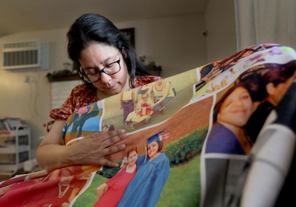 Vivian Zayas of Deer Park, Long Island looks at a blanket with family photos including those of her mother Ana Martinez May 11, 2022. Ana Martinez, 78, died in March of 2020 after contracting COVID-19 during what was to have been a temporary stay a nursing home following knee surgery. Zayas has founded Voices for Seniors, a nonprofit that advocates for residents of nursing homes and their families.