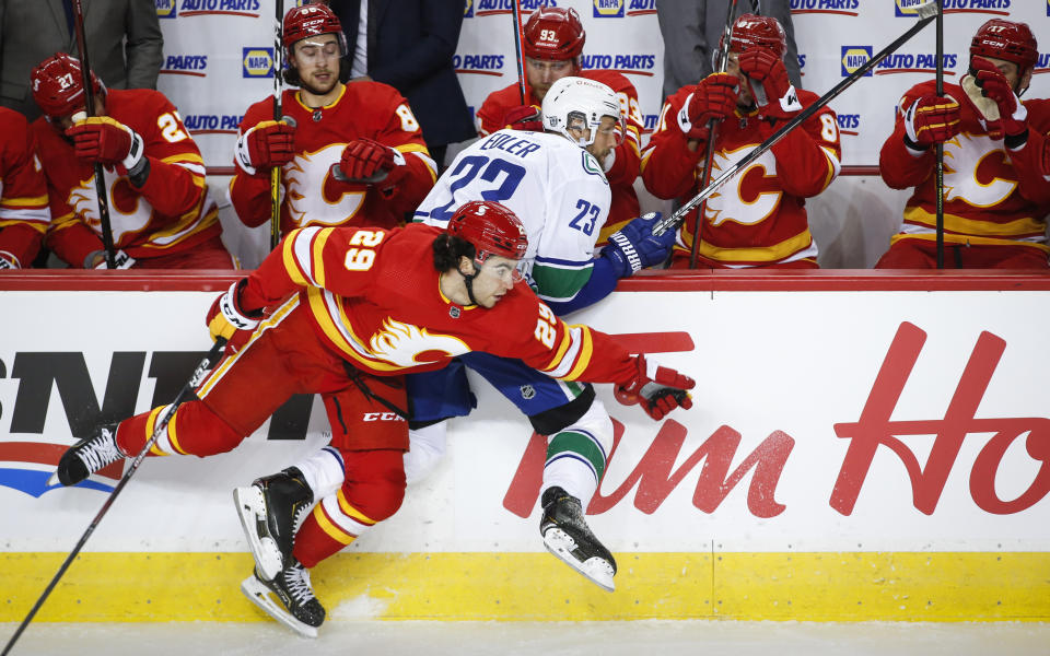 Vancouver Canucks' Alexander Edler, right, is checked by Calgary Flames' Dillon Dube during the first period of an NHL hockey game Saturday, Jan. 16, 2021, in Calgary, Alberta. (Jeff McIntosh/The Canadian Press via AP)