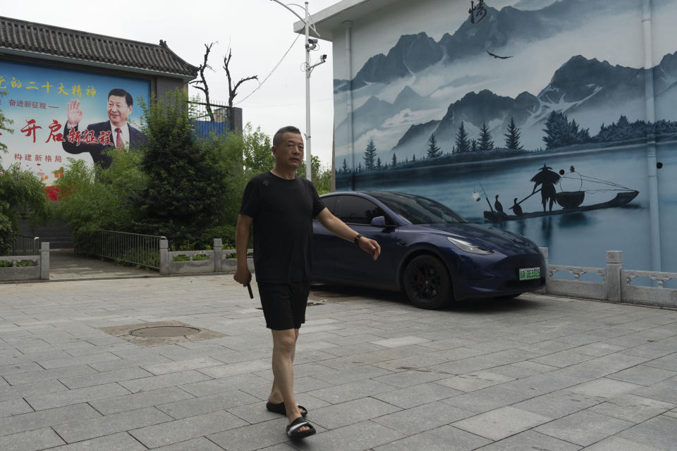 A man passes by a mural depicting Chinese President Xi Jinping with the slogan "Start a new journey" on the outskirts of Beijing, Thursday, July 25, 2024. (AP Photo/Ng Han Guan)