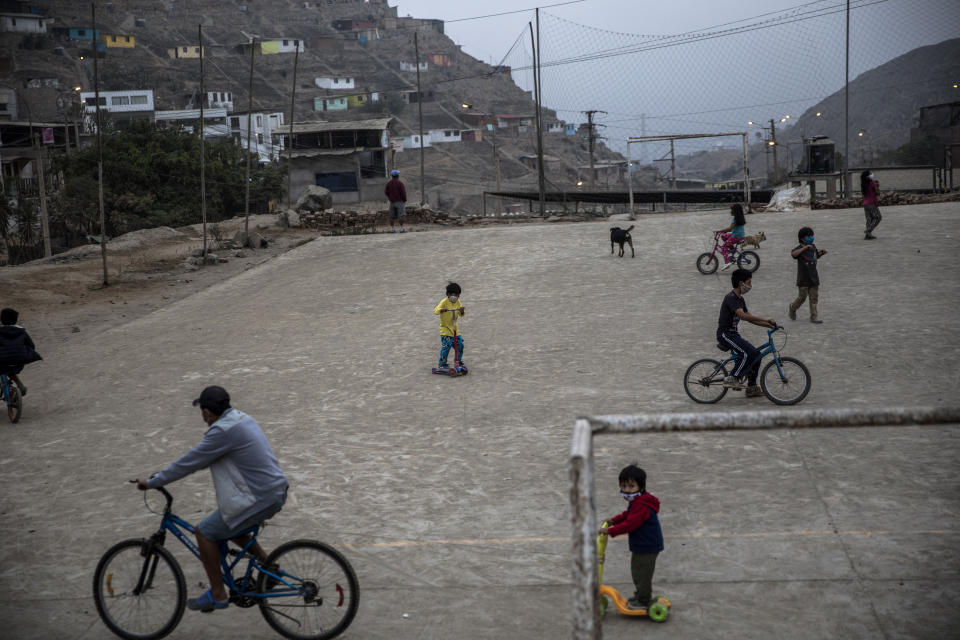 Los residentes montan bicicletas y scooters en un campo de fútbol comunitario en el barrio de Nueva Esperanza de Lima, Perú, el lunes 1 de junio de 2020. (AP Foto/Rodrigo Abd)