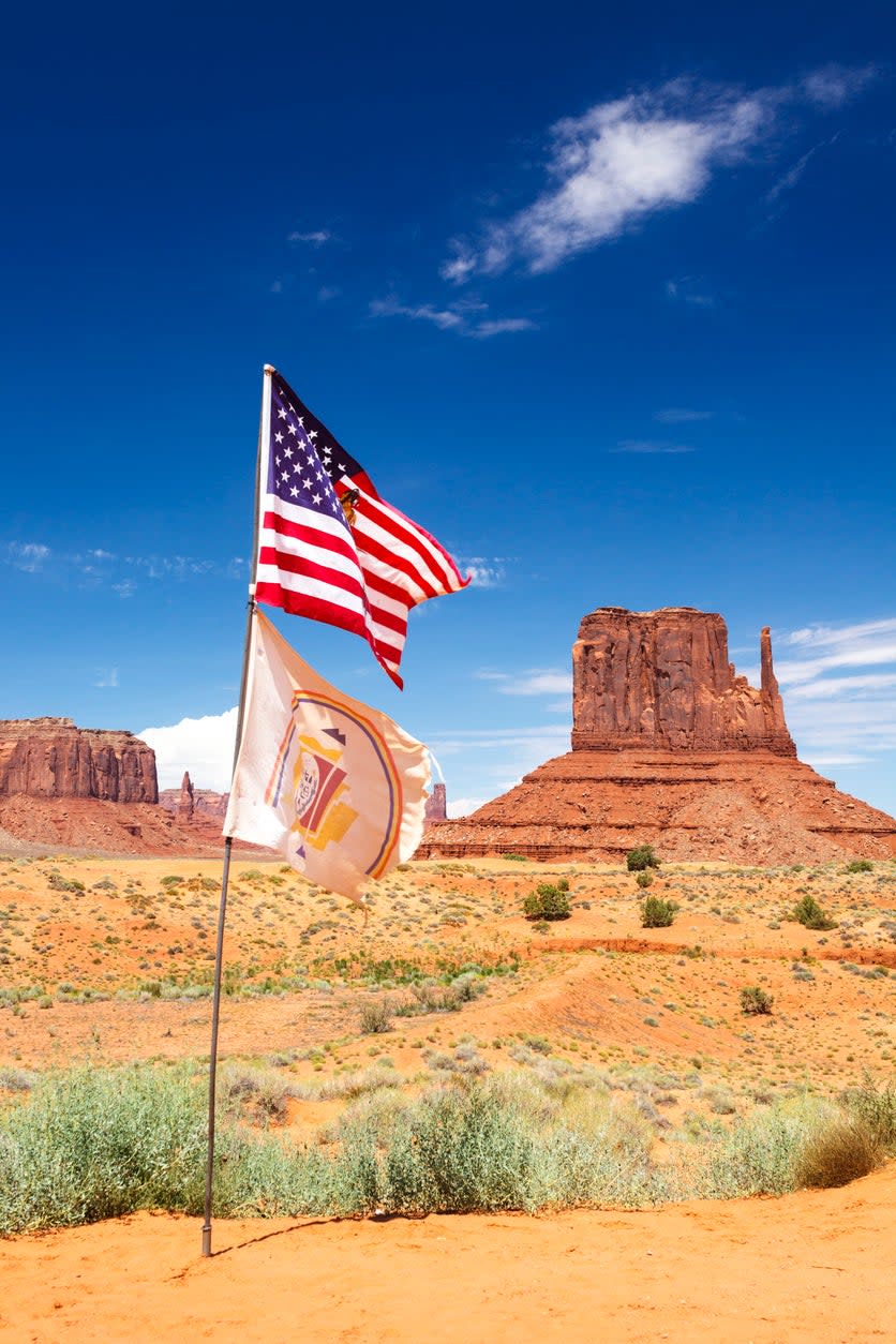 American flag and flag of the Navajo Nation. West Mitten Butte in background, Monument Valley Navajo Tribal Park, Arizona, United States.