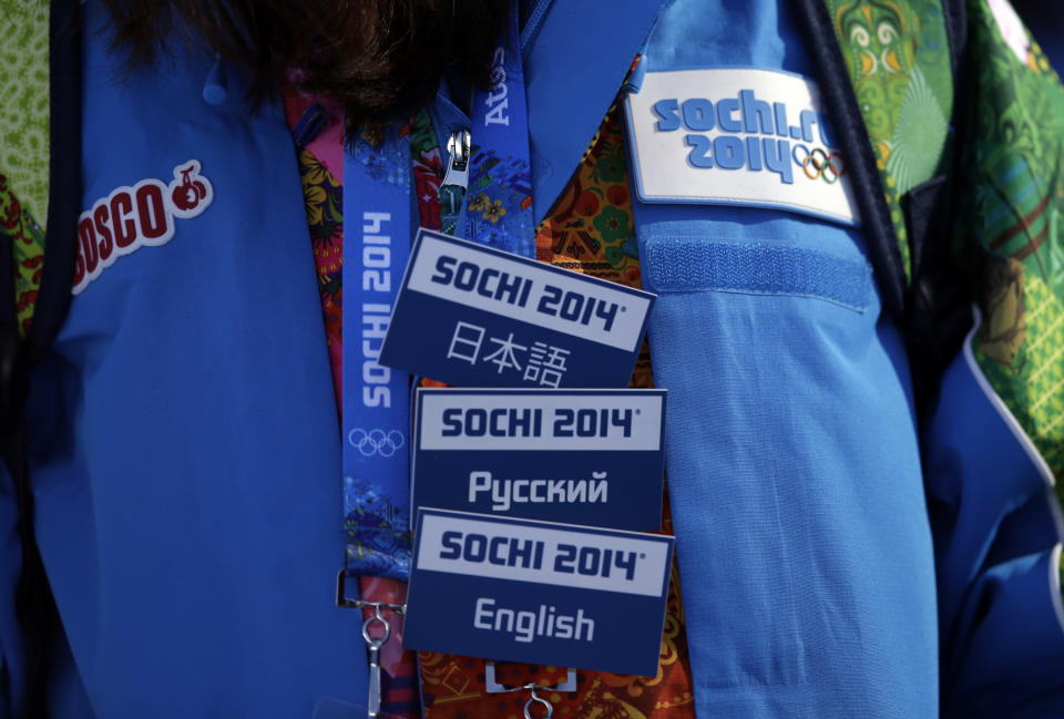 FILE - In this Feb. 6, 2014 file photo, a volunteer wears badges indicating the languages she speaks, during the men's snowboard slopestyle qualifying at the Rosa Khutor Extreme Park in Krasnaya Polyana, Russia, ahead of the 2014 Winter Olympics. More than 20 years after emerging from seven decades of Communism, many Russians, who long endured shabby Soviet construction and slow-moving workers, are encouraged by the progress they see in Sochi. The volunteer corps at the Olympics and staff at hotels have proved to be not just competent but friendly. (AP Photo/Andy Wong, File)