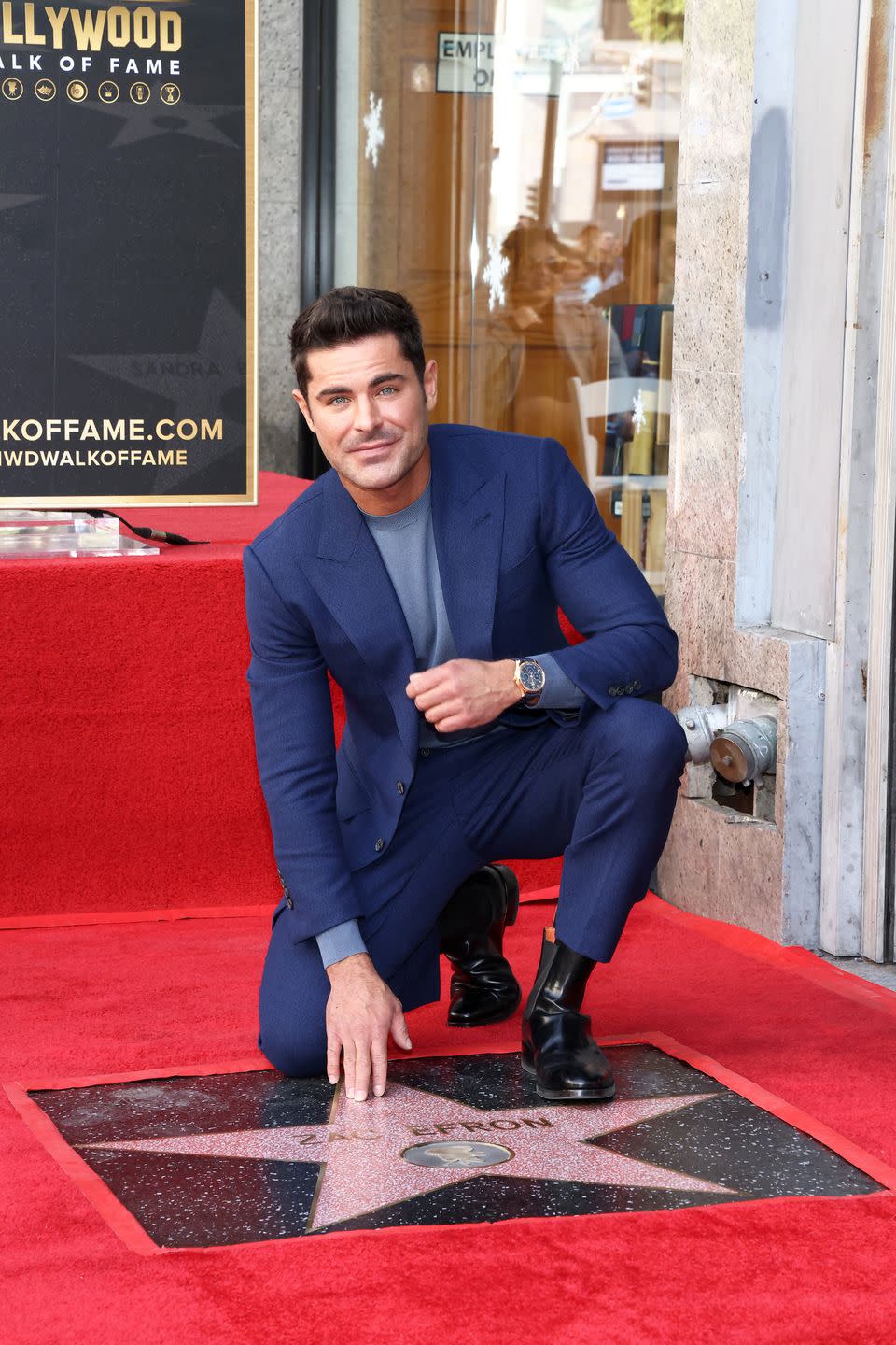 zac efron kneels next to his star on the hollywood walk of fame