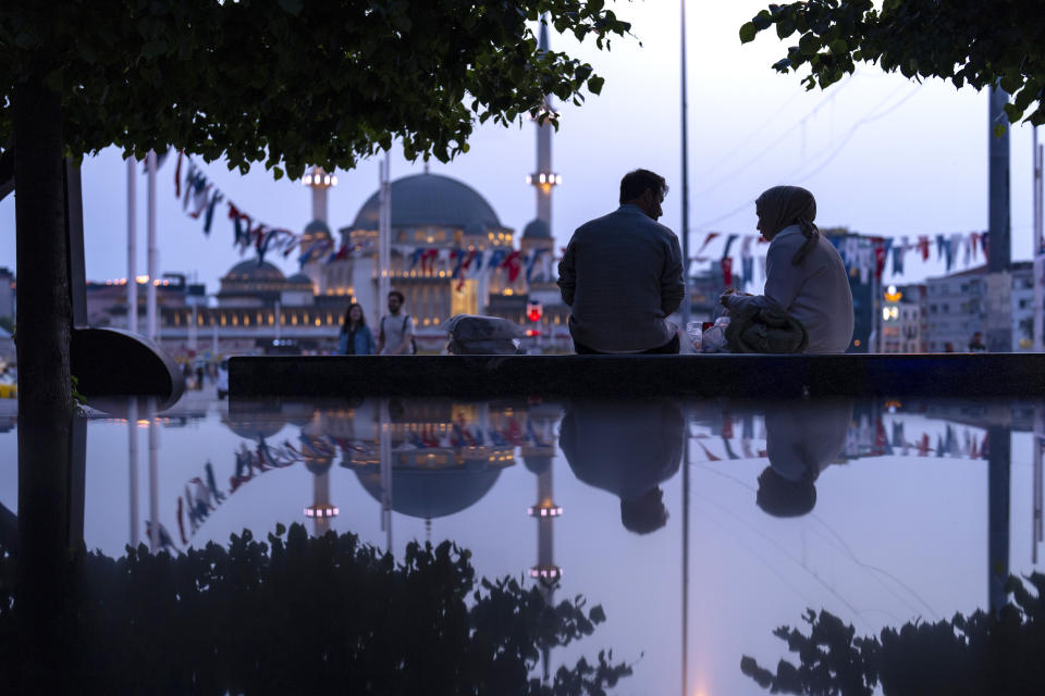 A couple sit in a public bench at Taksim square in Istanbul, Turkey, Wednesday, May 22, 2024. (AP Photo/Francisco Seco)