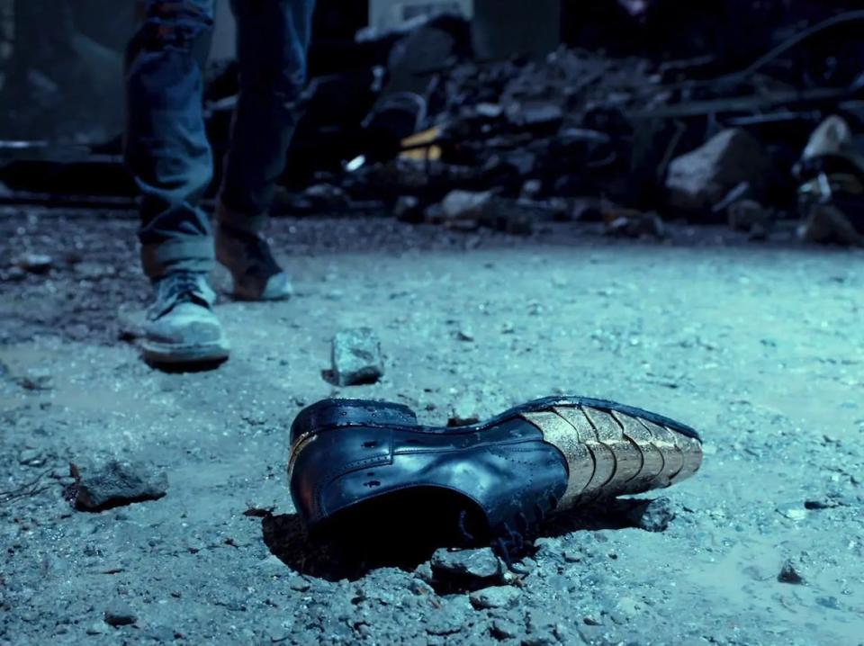 a single dress shoe plated with gold on the tip, lying in a pile of rubble