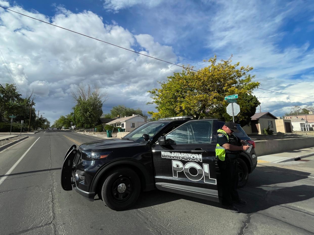 A police officer blocks traffic on a road following a deadly shooting Monday, May 15, 2023, in Farmington, New Mexico. Authorities said an 18-year-old opened fire in the northwestern New Mexico community, killing multiple people and injuring others, before law enforcement fatally shot the suspect.