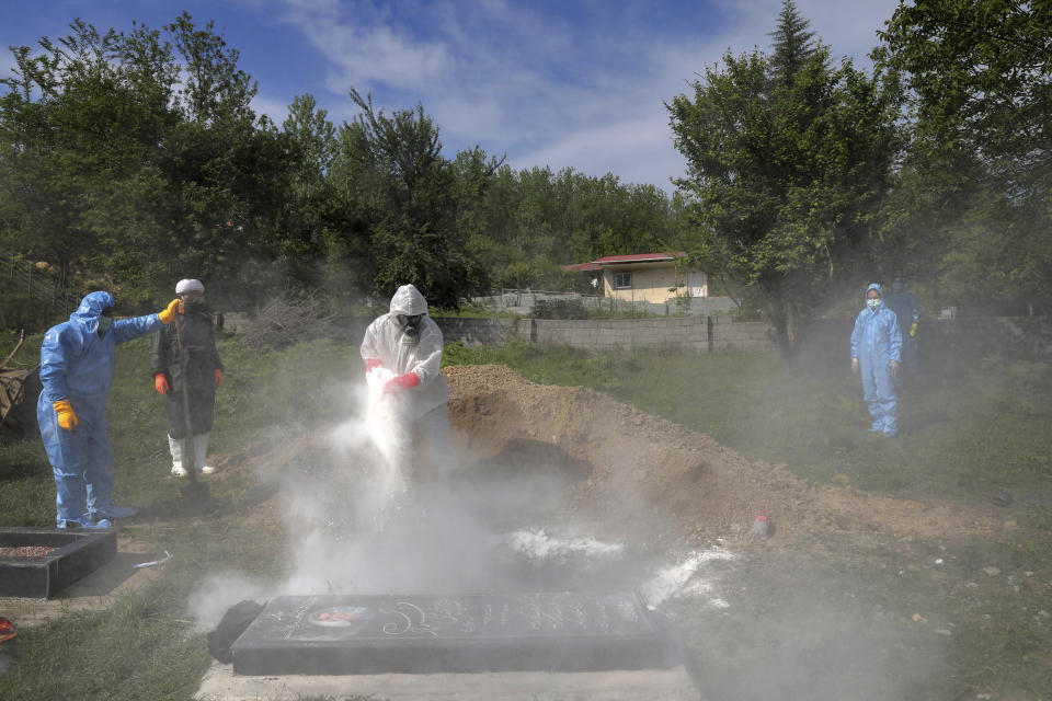 People wearing protective clothing attend the funeral of a victim who died from the coronavirus, at a cemetery in the outskirts of the city of Ghaemshahr in north of Iran, Friday, May 1, 2020. (AP Photo/Ebrahim Noroozi)