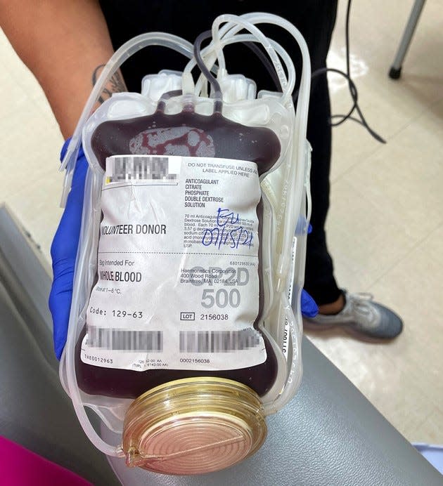 Phlebotomist Michelle Santiago holds up a pint of whole blood donated by TCPalm health, welfare and social justice reporter Lindsey Leake on Thursday, July 15, 2021, at the OneBlood donation center in Stuart, Fla. Leake, who is Black and white, donated for the first time when she learned from OneBlood that just 5% of Black Americans give blood. (Note: Bar codes have been blurred.)