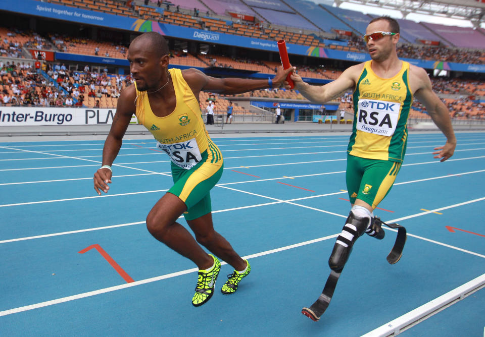 DAEGU, SOUTH KOREA - SEPTEMBER 01: Oscar Pistorius of South Africa passes the relay baton to Ofentse Mogawane of South Africa as they compete competes in the men's 4x400 metres relay heats during day six of the 13th IAAF World Athletics Championships at the Daegu Stadium on September 1, 2011 in Daegu, South Korea. (Photo by Alexander Hassenstein/Bongarts/Getty Images)