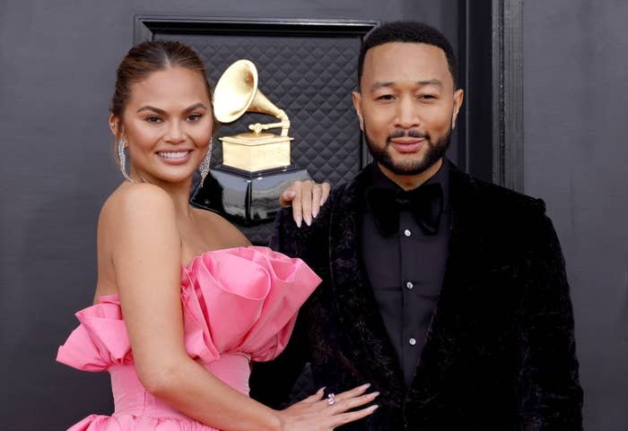 Chrissy with her hand on John's shoulder as they pose for photographers on the Grammys red carpet