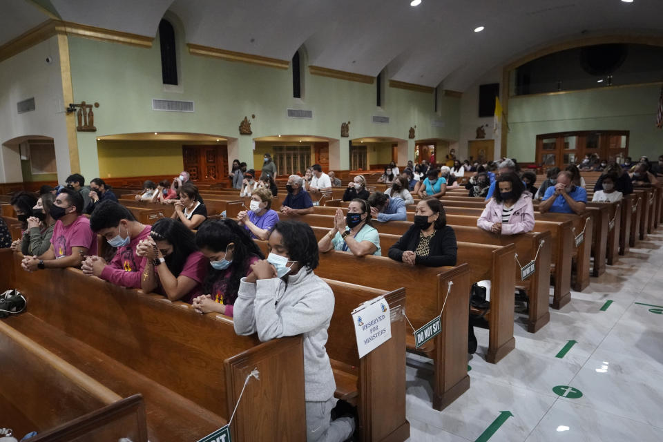 People pray, late Saturday, June 26, 2021, during a prayer vigil for the victims and families of the Champlain Towers collapsed building in Surfside, Fla., at the nearby St. Joseph Catholic Church in Miami Beach, Fla. Many people were still unaccounted for two days after Thursday's fatal collapse. (AP Photo/Wilfredo Lee)