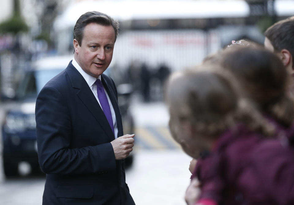 British Prime Minister David Cameron talks to school children as he returns to 10 Downing Street in London, Wednesday, March 26, 2014. (AP Photo/Sang Tan)