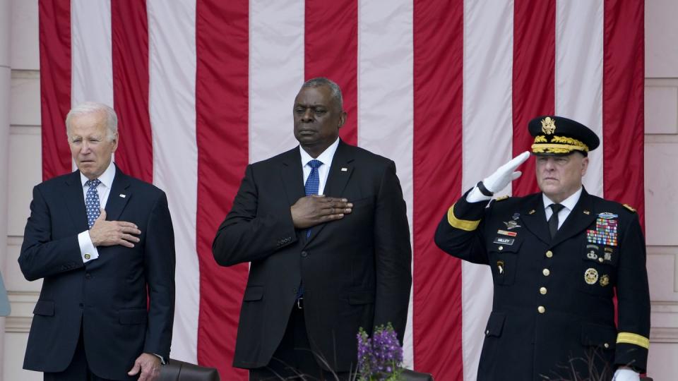 President Joe Biden holds his hand on his heart as he stands with Defense Secretary Lloyd Austin and Chairman of the Joint Chiefs of Staff Gen. Mark Milley during the playing of 