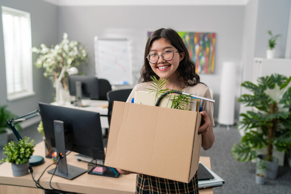 Woman carrying her things out of her office after quitting a job