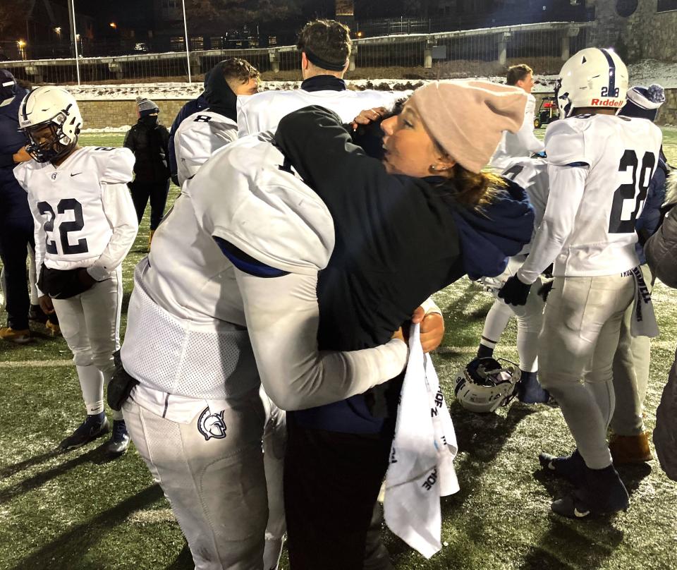 McDowell fan Gia Glass hugs Trojans' football player Christian Santiago after Friday's PIAA Class 6A playoff game at State College's Memorial Field. State College linebacker Michael Gaul recovered Santiago's fumble during McDowell's third overtime possession. The play ended the Little Lions' dramatic 57-50 victory.