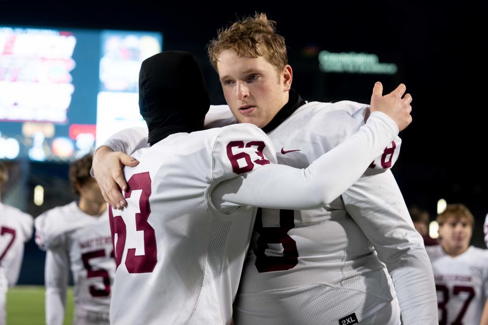 Nate Kreuz (78) hugs Luke Fivecoat (63) after Watterson's 27-7 loss to Toledo Central Catholic in the Division III state final Friday at Tom Benson Hall of Fame Stadium in Canton.