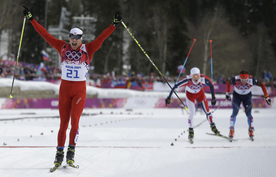 Switzerland's Dario Cologna celebrates winning the gold medal as Norway's Martin Johnsrud Sundby, second from right, and Russia's Maxim Vylegzhanin are to cross the finish line during the men's cross-country 30k skiathlon at the 2014 Winter Olympics, Sunday, Feb. 9, 2014, in Krasnaya Polyana, Russia. (AP Photo/Gregorio Borgia)