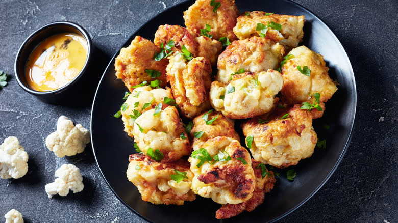 battered cauliflower florets on plate sitting on granite counter