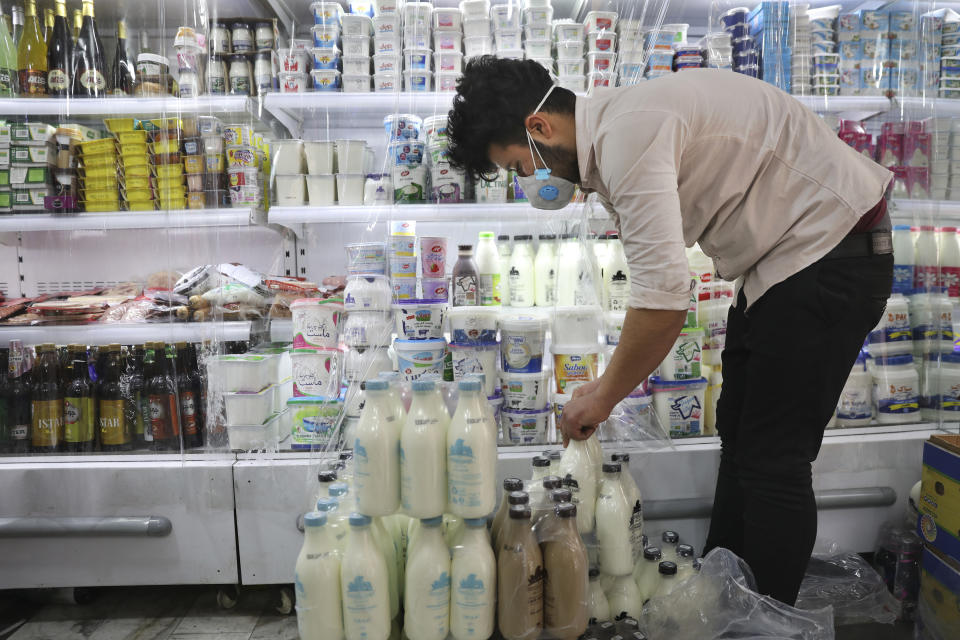 In this Tuesday, April 21, 2020 photo, grocery deliveryman Saeed Vatanparast, wearing a protective face mask to help prevent the spread of the coronavirus, works at a store in Tehran, Iran. For some $15 a day, deliverymen don masks and gloves in Iran's capital to zip across its pandemic-subdued streets to drop off groceries and food for those sheltering at home from the virus. (AP Photo/Vahid Salemi)