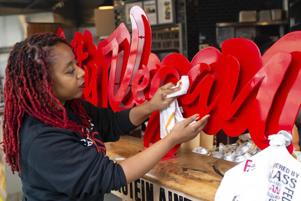 In this Wednesday, May 20, 2020, photo, Pinky Cole, owner of Slutty Vegan restaurants and food trucks, wipes down a sign on her storefront in Atlanta. Through her Pinky Cole Foundation, she’s been paying the rent for small businesses that are struggling. “Black-owned businesses, we’ve always landed at the bottom of the totem pole as it relates to resources,” Cole said. “We put our blood, sweat and tears into these businesses and everything you’ve worked hard for can be lost in a matter of days.” (AP Photo/Angie Wang)