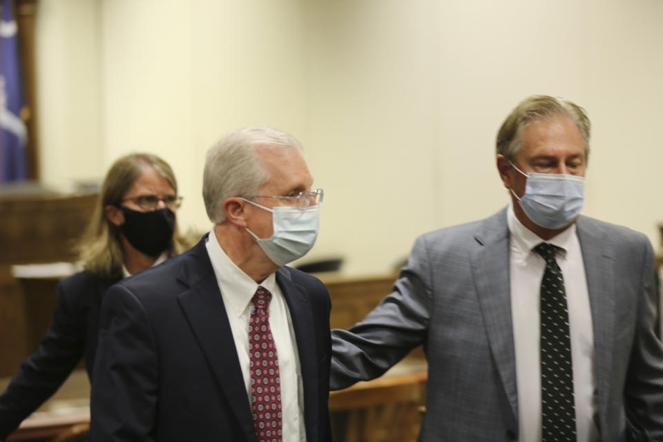 Former SCANA CEO Kevin Marsh, center, is led out of the courtroom by attorney Robert Bolchoz, right, after a South Carolina judge accepted a plea deal that included a two-year federal prison term for Marsh on Monday, Oct. 11, 2021, in Spartanburg, S.C. Marsh is the first executive to go to prison for the failed project to build two nuclear reactors which cost ratepayers billions of dollars and never generated a watt of power. (AP Photo/Jeffrey Collins)
