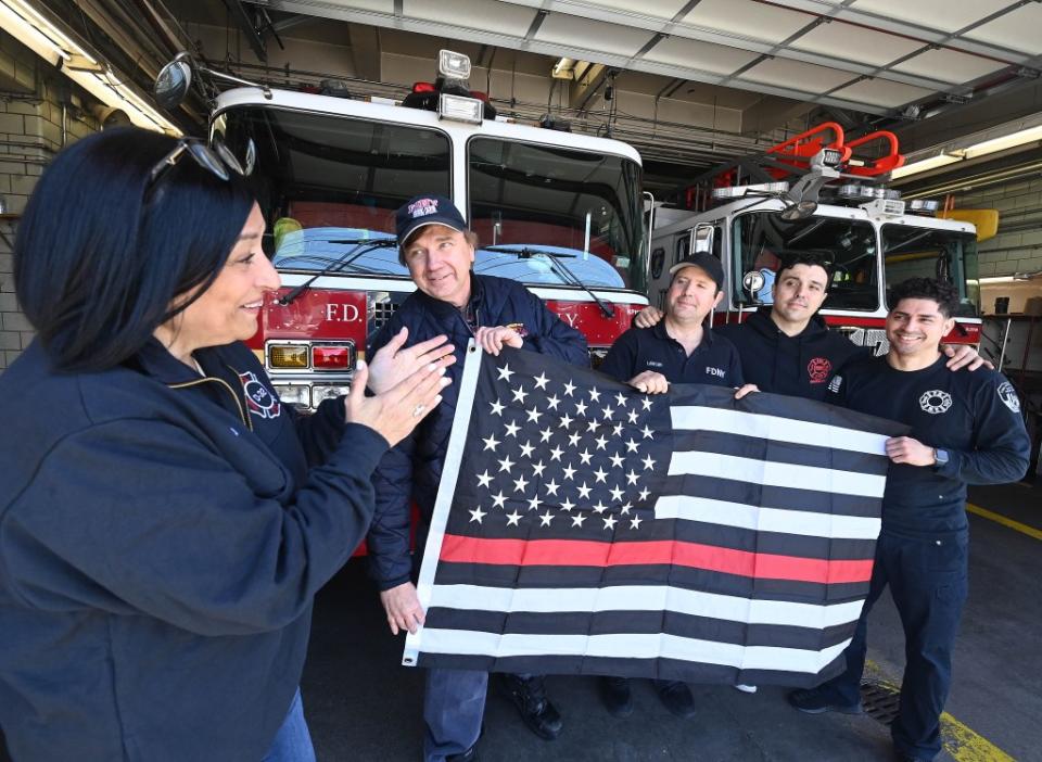 Ariola delivers a “red-line” flag on Friday to firefighters from Engine Company 331/Ladder Company 173 in Howard Beach. Helayne Seidman