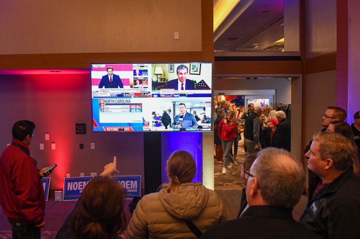 Watch party-goers gather around a television with multiple national broadcasts of election results on Tuesday evening, November 8, 2022, at the Hilton Garden Inn in Sioux Falls.