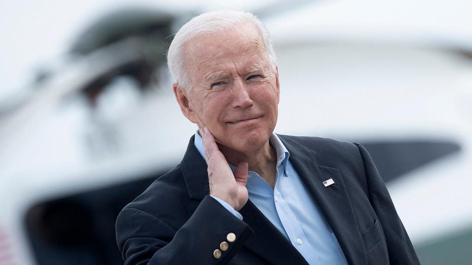 President Biden wipes his neck after a cicada landed on him before boarding Air Force One at Joint Base Andrews Wednesday. (Photo by Brendan Smialowski/AFP via Getty Images)