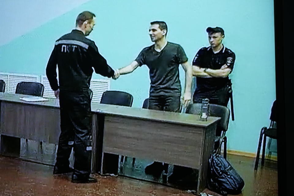 Russian opposition leader Alexei Navalny, left, and his associate Daniel Kholodny are seen at a TV screen shaking hands as they appear in a video link provided by the Russian Federal Penitentiary Service, during a hearing in the colony, in Melekhovo, Vladimir region, about 260 kilometers (163 miles) northeast of Moscow, Russia, on Friday, Aug. 4, 2023. Navalny on Friday was convicted on extremism charges and sentenced to 19 years in prisons, in the harshest ruling against the imprisoned Kremlin critic to date. (AP Photo/Alexander Zemlianichenko)