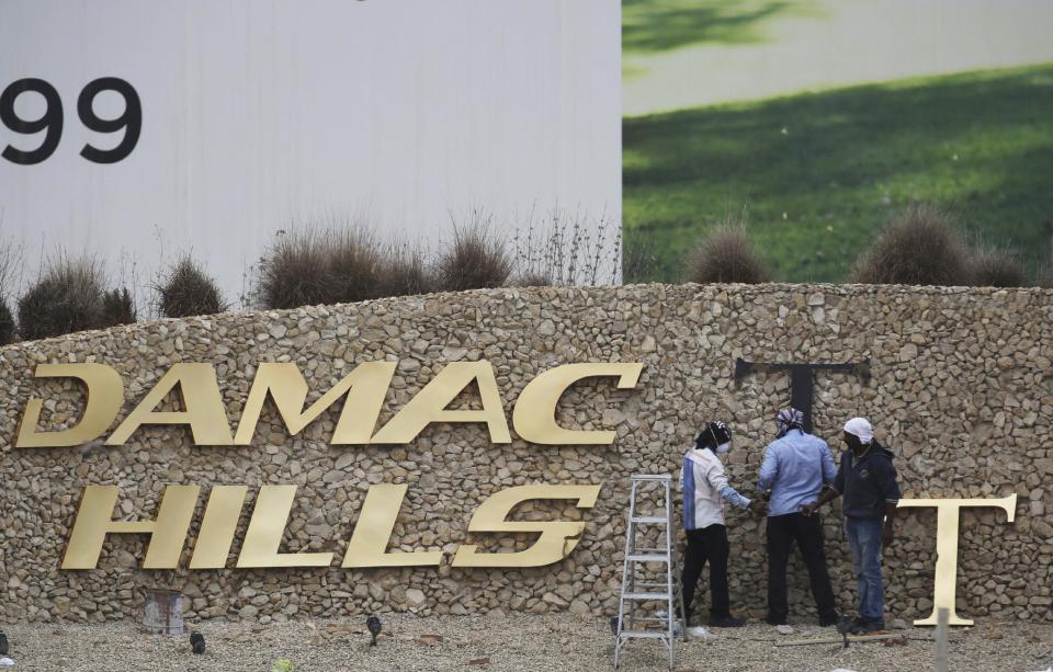 FILE- In this Sunday, Feb. 12, 2017 file photo, workers re-install a gold letter sign for the Trump International Golf Club in Dubai, United Arab Emirates. U.S. President Donald Trump's two sons in charge of his business empire will attend a closed-door event to mark the opening of the Trump International Golf Club in Dubai. (AP Photo/Jon Gambrell, File)