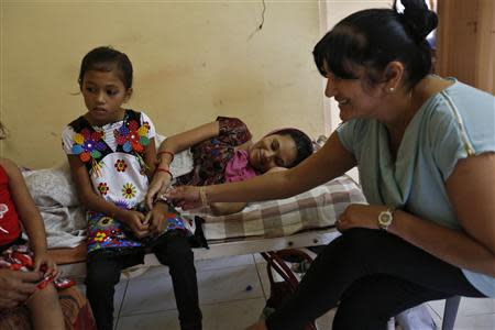 Rekha Patel (R), 42, from Britain, touches surrogate mother Naina Patel's (C) biological daughter inside a temporary home for surrogates provided by Akanksha IVF centre in Anand town, about 70 km (44 miles) south of the western Indian city of Ahmedabad August 25, 2013. REUTERS/Mansi Thapliyal