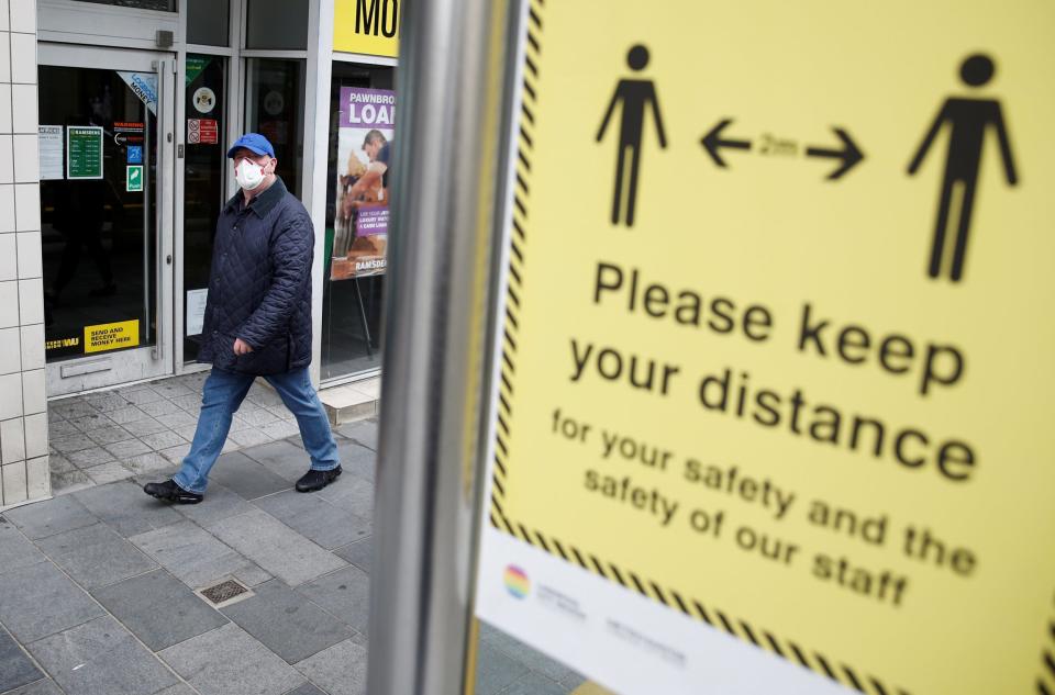 A man wearing a face mask walks by a social distance sign in Liverpool (REUTERS)