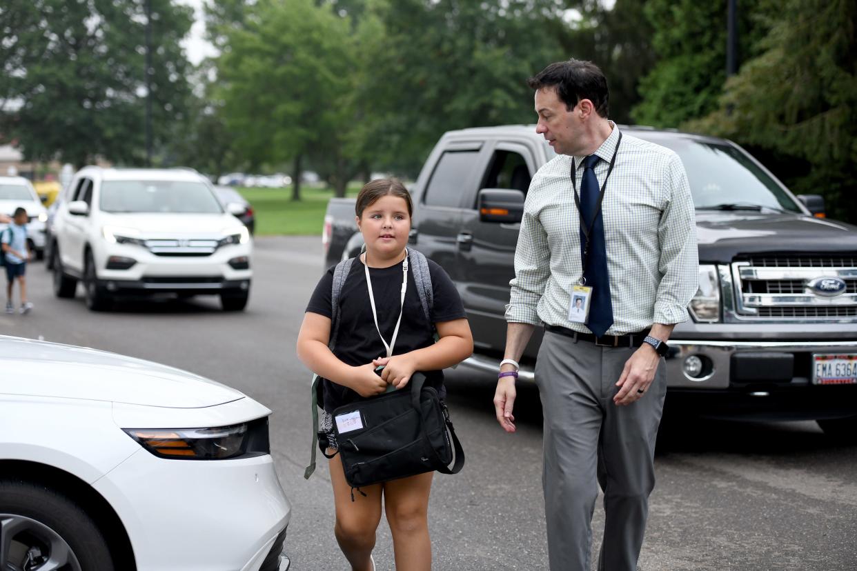 Principal J.R. Reindel welcomes fourth grade student Eva Leggett, 10, back to school at Sauder Elementary in Jackson Township for her first day of class last week.