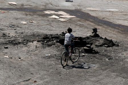 A boy rides a bicycle near a hole in the ground after an airstrike on Sunday in the rebel-held town of Dael, in Deraa Governorate, Syria September 19, 2016. REUTERS/Alaa Al-Faqir