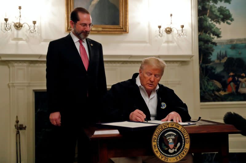 U.S. President Donald Trump accompanied by Health and HHS Secretary Alex Azar, signs the Congressional funding bill for coronavirus response at the White House in Washington