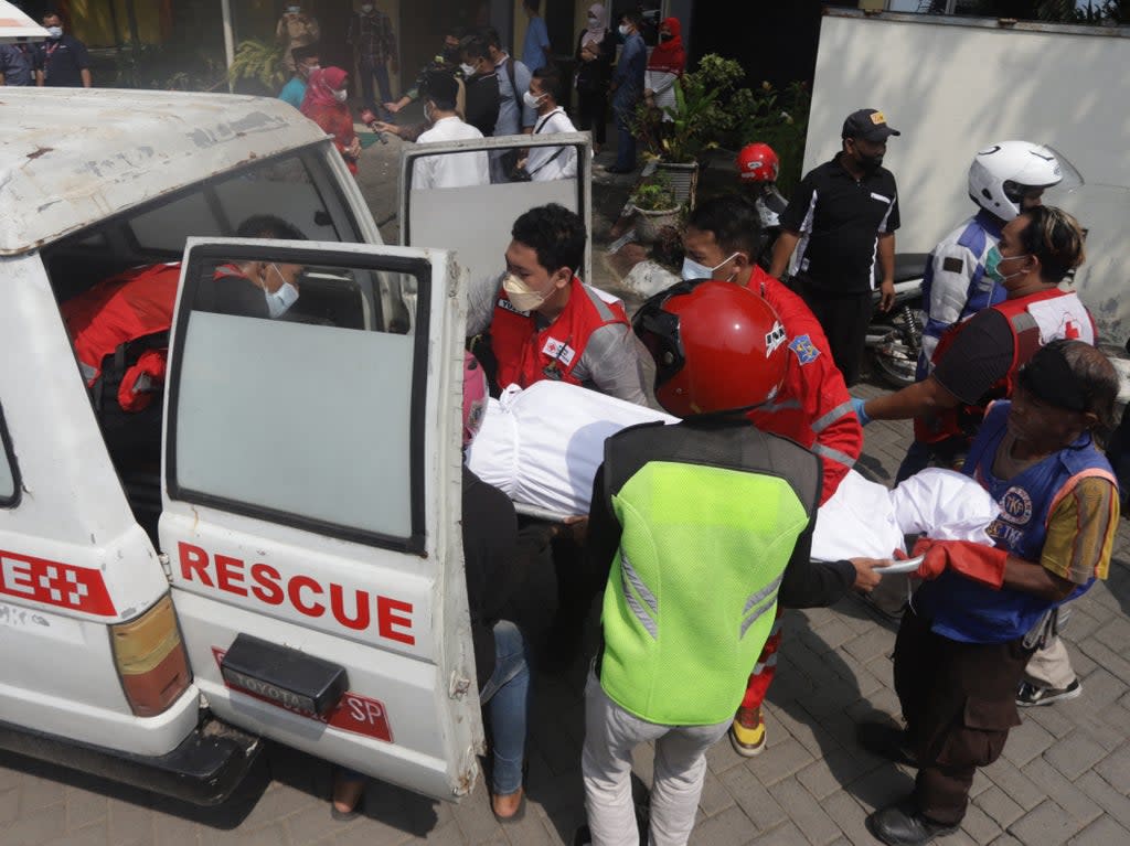 Medical workers load a victim’s body into a vehicle after a bus crash in Mojokerto on 16 May 2022 (AFP via Getty Images)