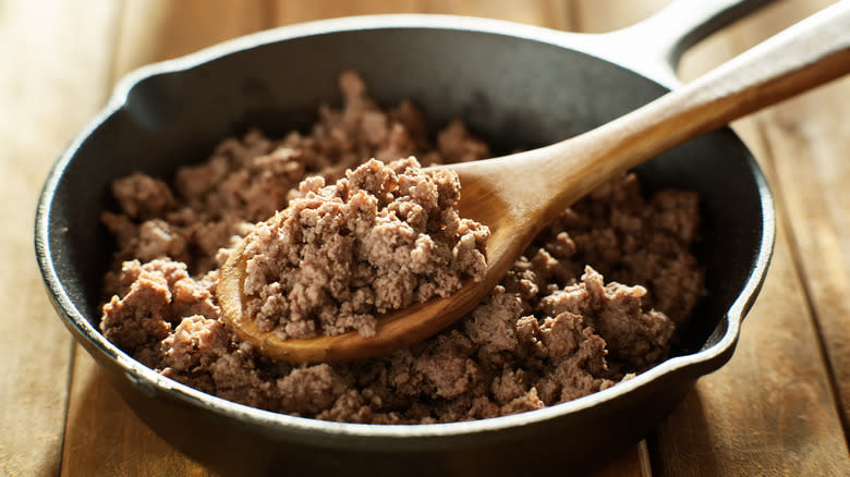 Ground meat in skillet with wooden spoon