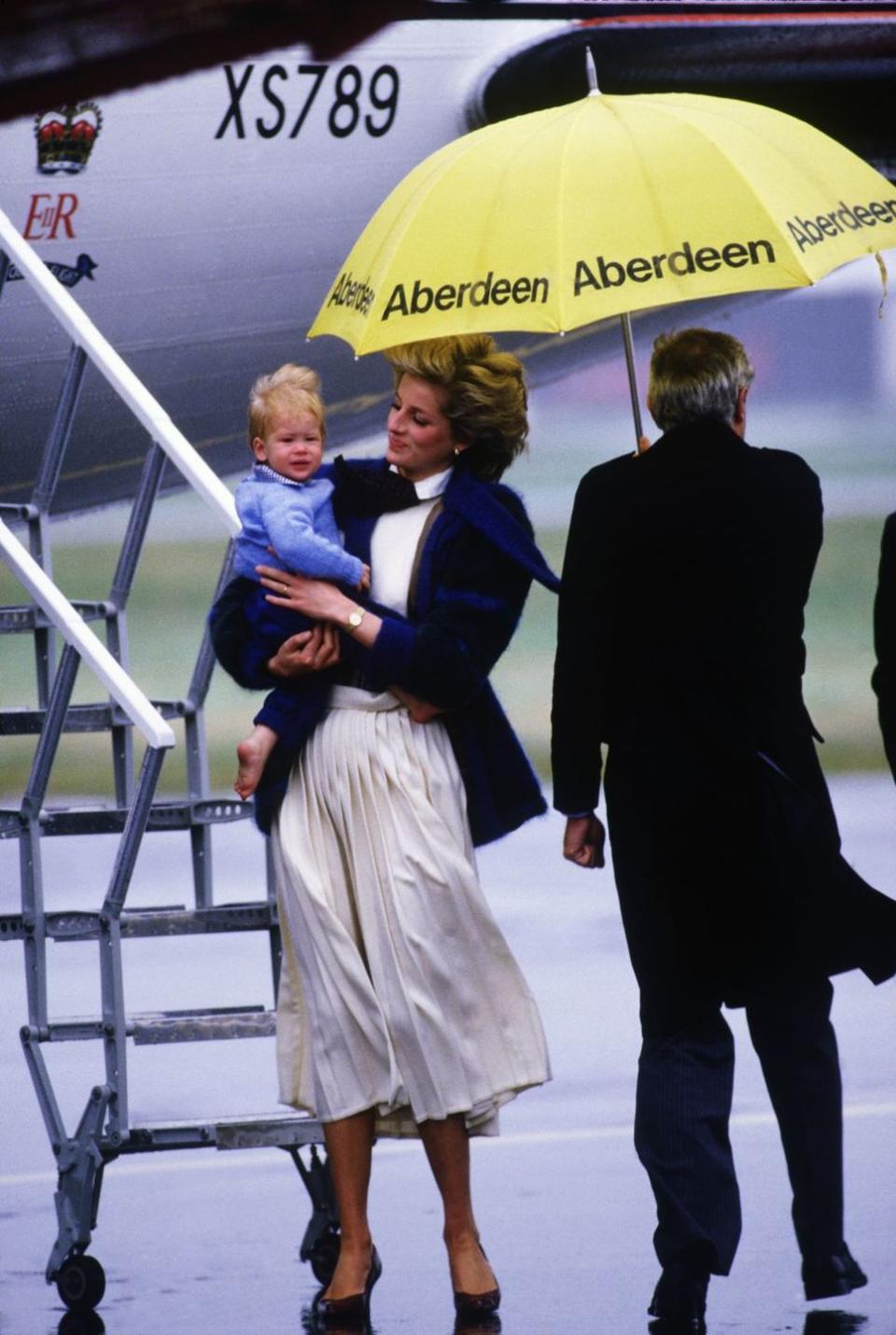 <p>A man sort of, not really protects Princess Diana and Prince Harry from the elements.<br></p>