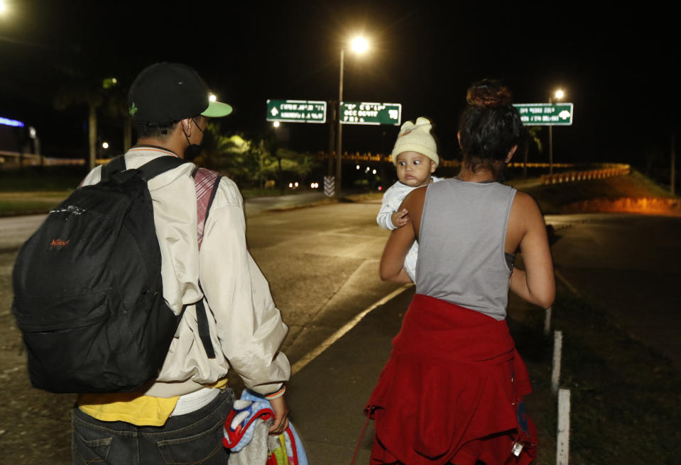 Migrants who aim to reach the U.S. walk with a bigger group along a highway as they leave San Pedro Sula, Honduras before dawn Tuesday, March 30, 2021. (AP Photo/Delmer Martinez)