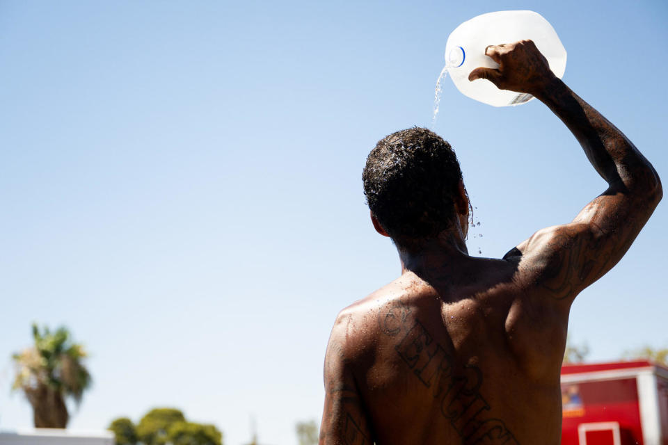 Image; A man pours water over his head from a gallon jug amid soaring temperatures in Phoenix on July 16.  (Brandon Bell / Getty Images file)