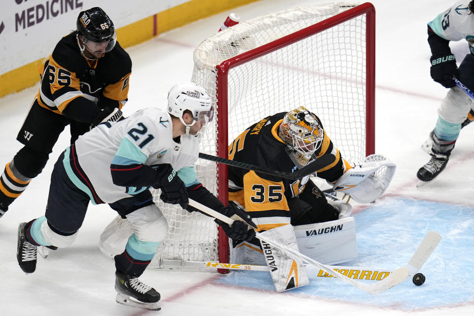 Pittsburgh Penguins goaltender Tristan Jarry (35) blocks a shot attempt by Seattle Kraken's Alex Wennberg (21) with Erik Karlsson (65) defending during the first period of an NHL hockey game in Pittsburgh, Monday, Jan. 15, 2024. (AP Photo/Gene J. Puskar)