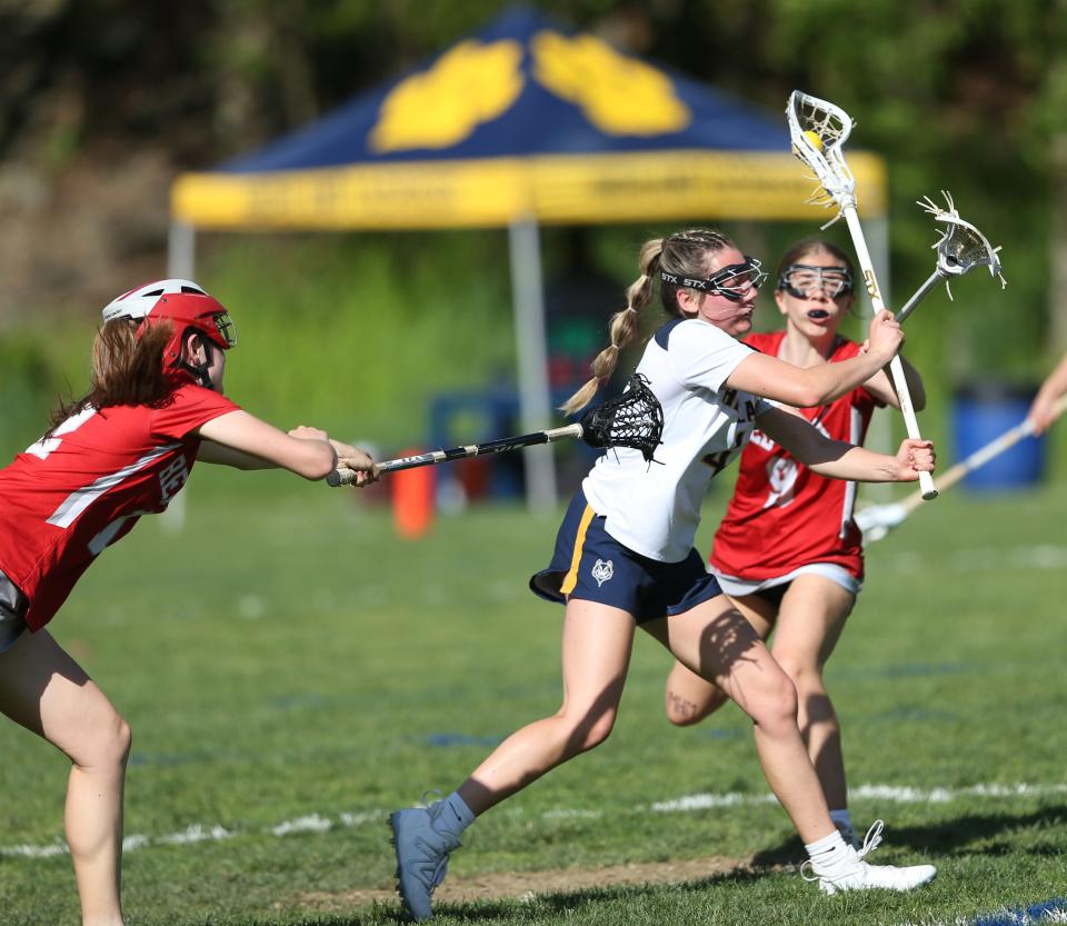 Highland's Logan VanZandt breaks through Red Hook defenders, from left, Eleanor Solomon and Anna Finch to score during a game on May 8, 2024.