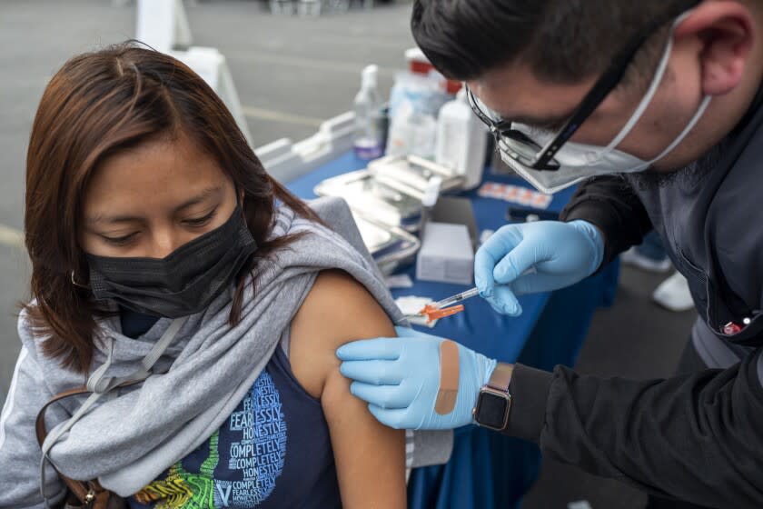 LOS ANGELES, CA - JANUARY 29: Micheal Federico, right, gives Ivonn Cruz, 30, left, a vaccinination at the historic First African Methodist Episcopal Church (FAME) on Saturday, Jan. 29, 2022 in Los Angeles, CA. L.A. Care Health Plan has partnered with the historic First African Methodist Episcopal Church (FAME) to offer free COVID-19 vaccines, including first, second and booster doses, as well as COVID-19 testing. The free event is open to the public. (Francine Orr / Los Angeles Times)