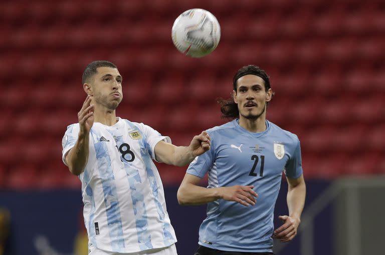 Guido Rodríguez se posiciona para controla la pelota ante Edinson Cavani