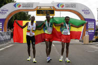 Gold medalist Tamirat Tola, of Ethiopia, center, stands with silver medalist Mosinet Geremew, of Ethiopia, right, and bronze medalist Bashir Abdi, of Belgium, after the men's marathon at the World Athletics Championships on Sunday, July 17, 2022, in Eugene, Ore. (AP Photo/Gregory Bull)